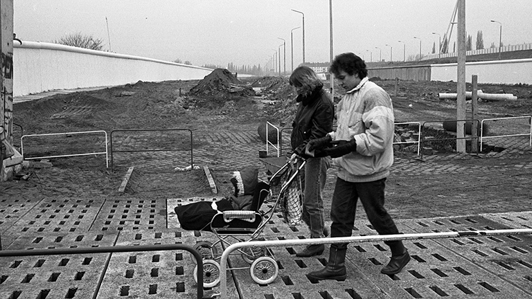 Ein Paar schiebt einen Kinderwagen über einen Grenzübergang.