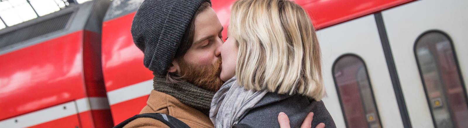 Ein Paar verabschiedet sich auf einem Bahnsteig in Hamburg voneinander