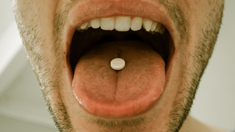 Ein Mann schluckt eine weiße Pille.