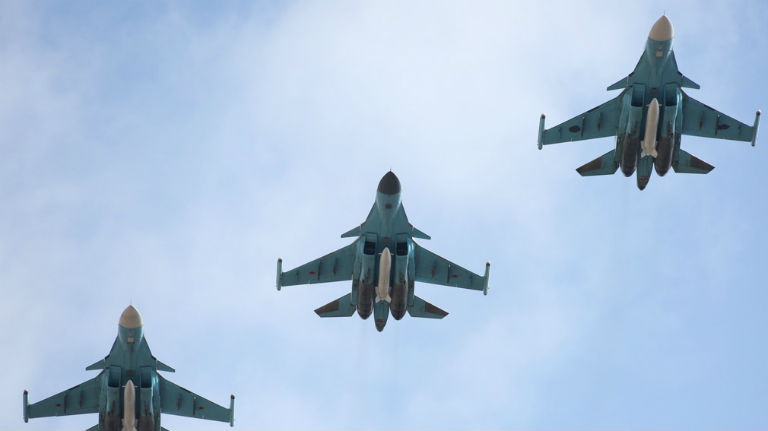 Drei russische SU 34 Kampfjets fliegen vor blauem Himmel.