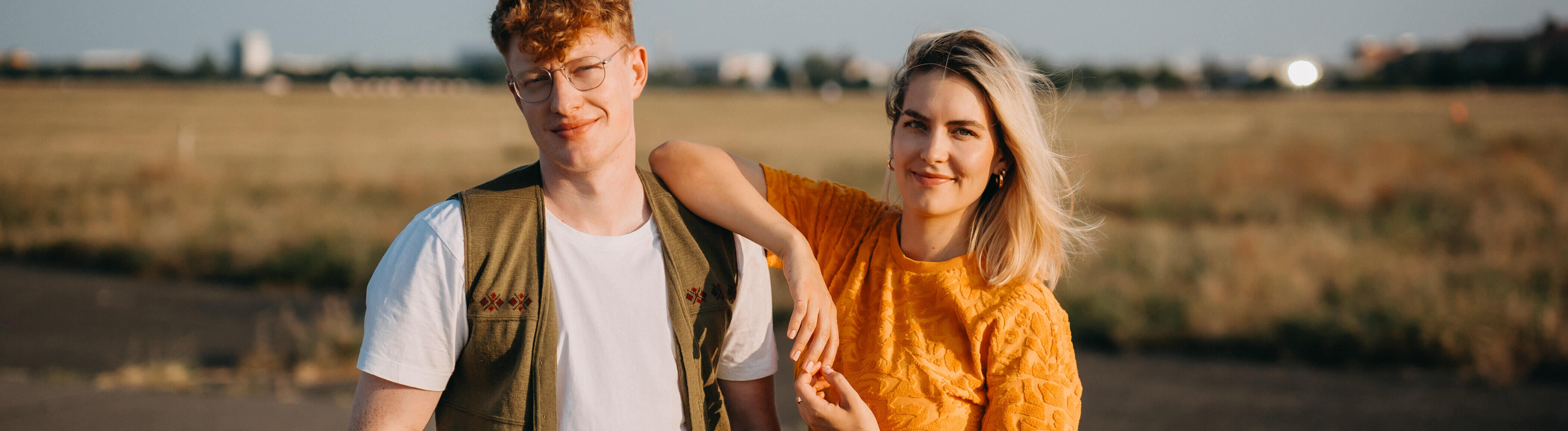 Die beiden Hosts vom Deutschlandfunk-Nova-Podcast "Facts und Feelings" stehen nebeneinander auf dem Tempelhofer Feld in Berlin. Die Hosts sind Przemek Żuk und Shalin Rogall.