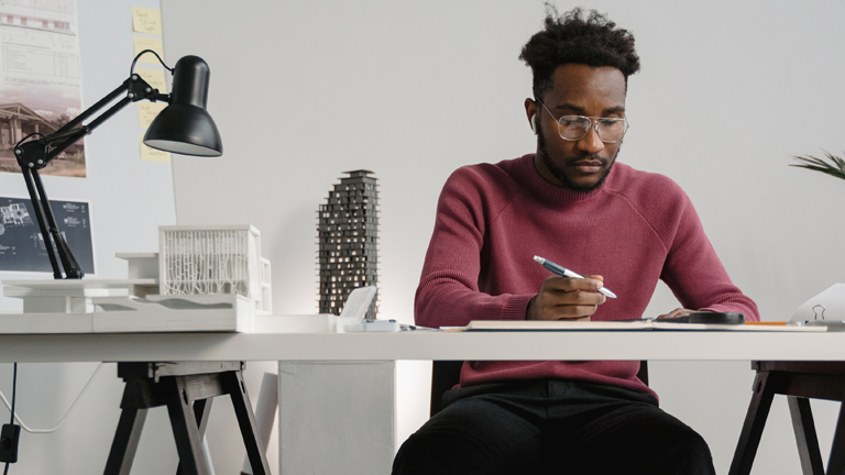 Ein Mann sitzt am Schreibtisch und arbeitet.