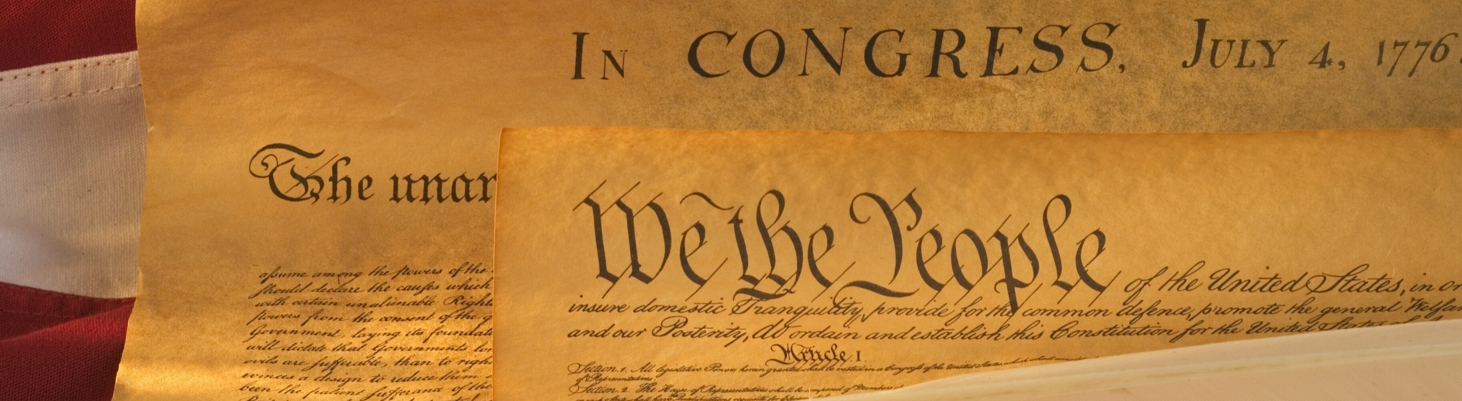 Das historische Dokument mit der amerikanischen Verfassung liegt auf der amerikanischen Flagge. Auf dem Dokument liegt eine Schreibfeder in Weiß.