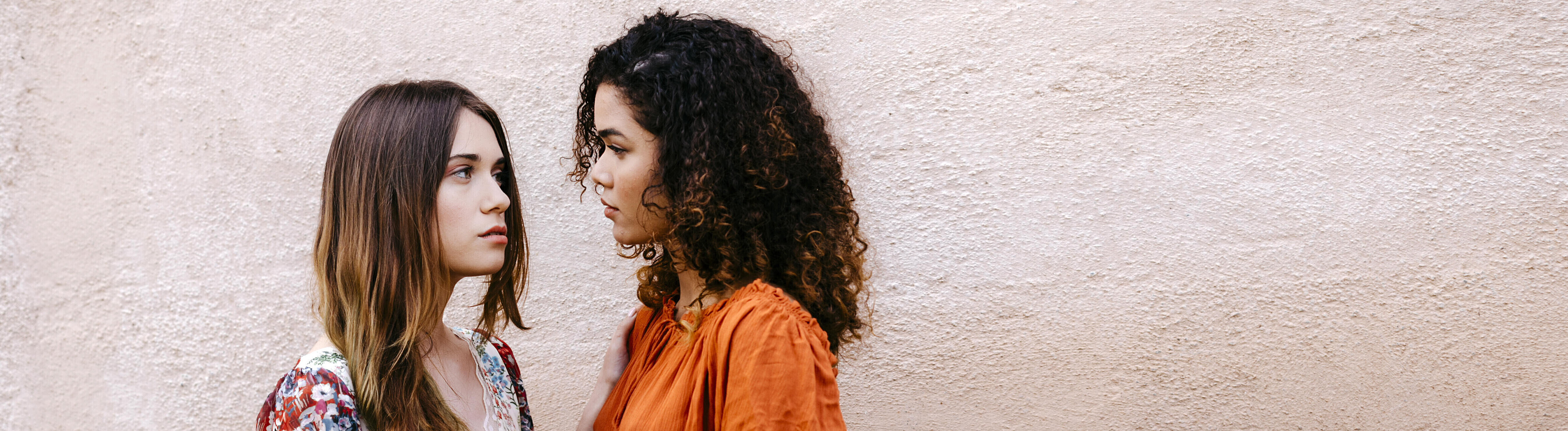 Zwei Frauen halten sich an den Händen und schauen sich skeptisch an