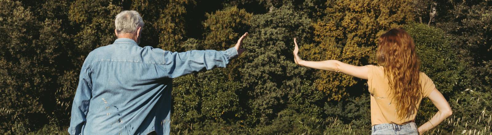 Mann und Frau stehen auf einer Wiese und zeigen eine armlänge Abstand zueinander