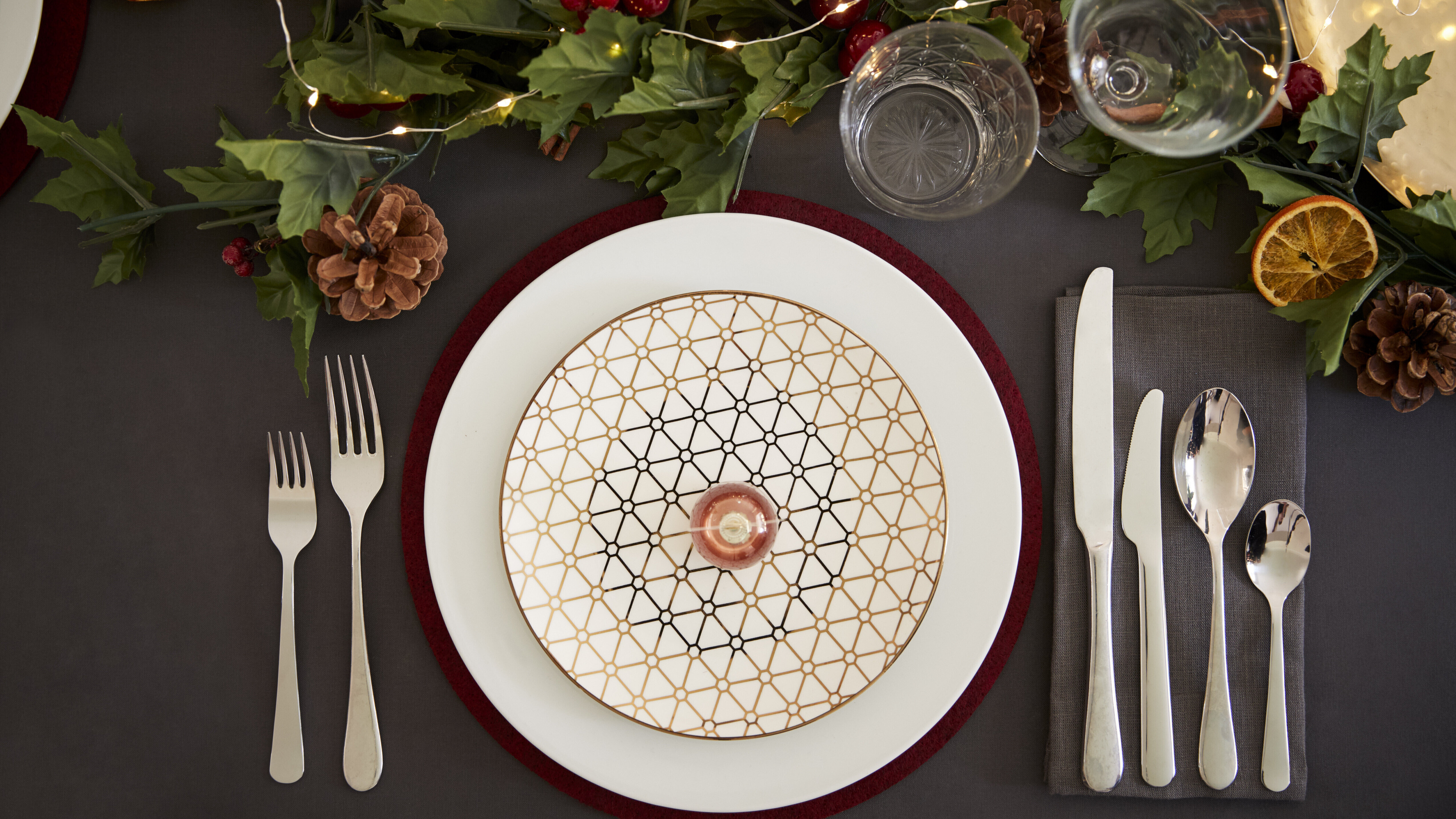 Ein Teller und Besteck an einem weihnachtlich geschmückten Esstisch.