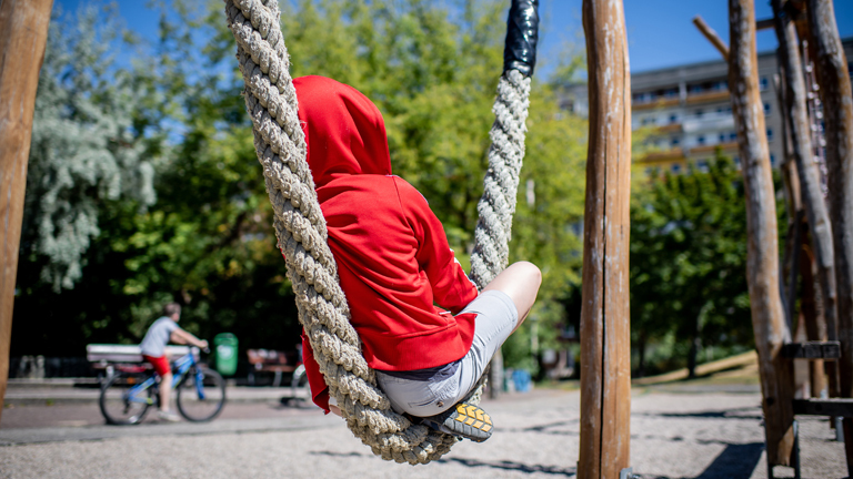 31. Juli 2020: Leipzig (Sachsen), Stadtteil Gruenau: Ein Kind sitzt auf einem Spielplatz vor einem Plattenbau in Leipzig-Gruenau. Foto: Thomas Eisenhuth