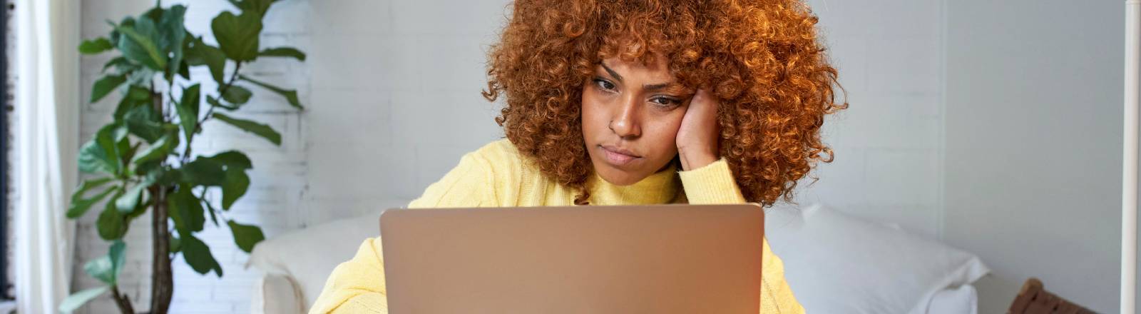 Eine Frau sitzt gelangweilt vorm Laptop
