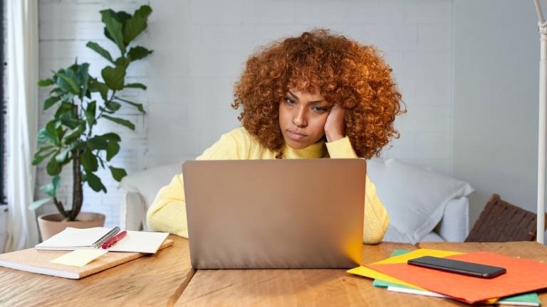 Eine Frau sitzt gelangweilt vorm Laptop