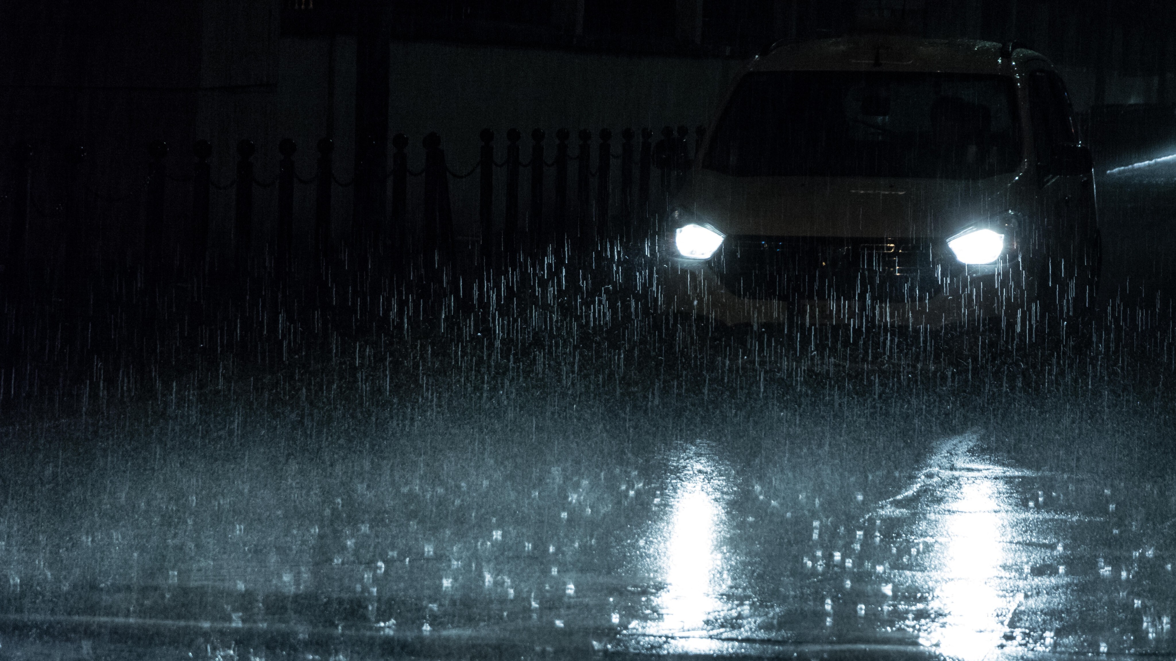 Scheinwerfer eines Autos bei Nacht und im Regen.