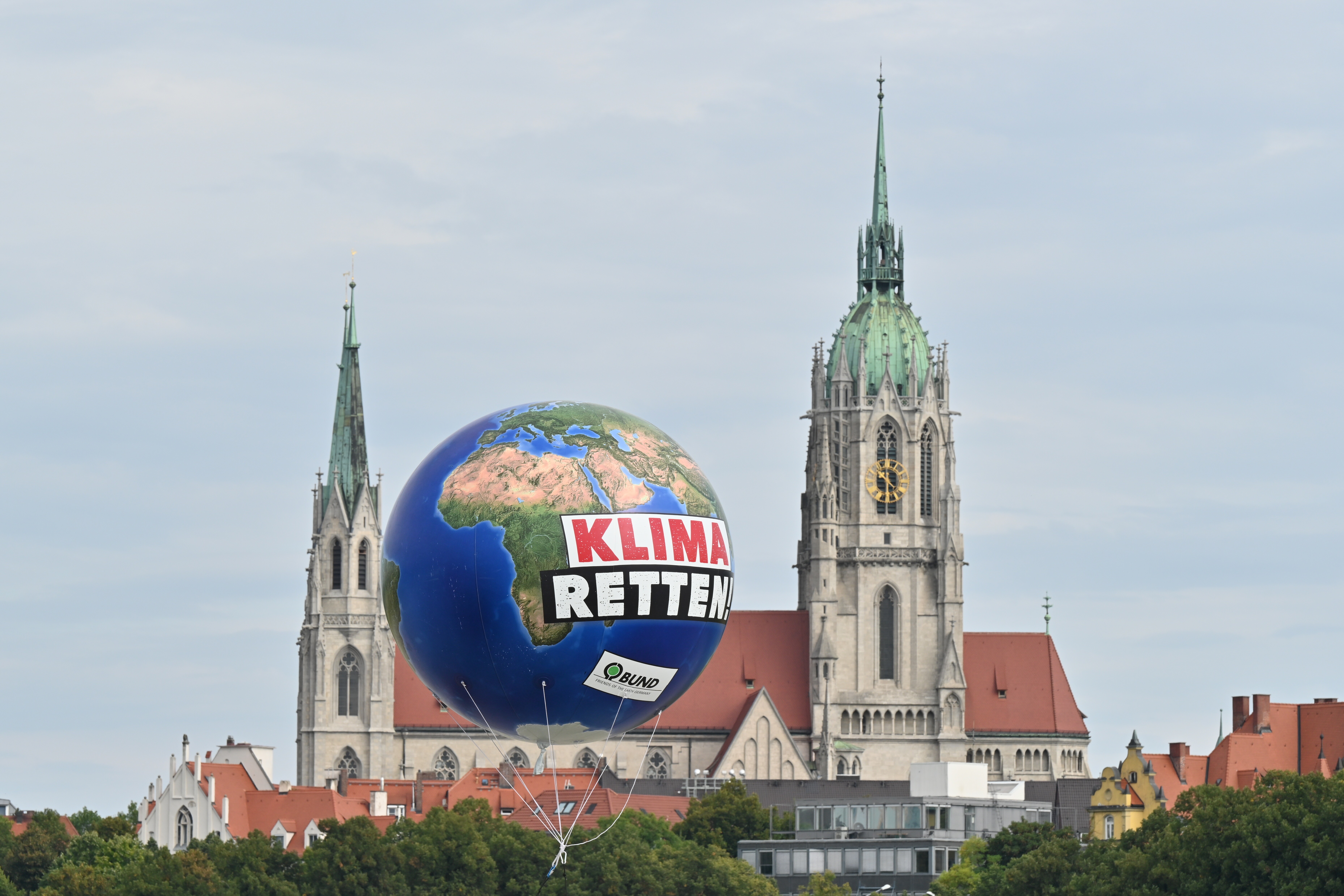 Ein Ballon mit der Aufschrift „Klima Retten“ schwebt vor einer Kirche