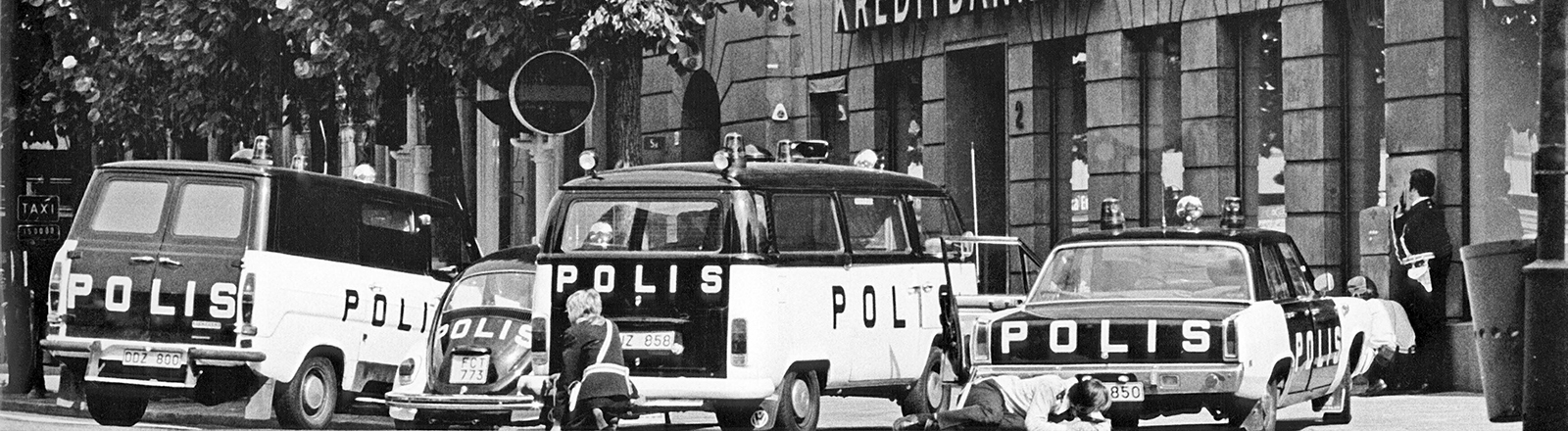 Archivfoto in schwarz-weiß: Polizeiautos stehen vor einem Gebäude. Kreditbanken und Bank steht an dem Haus. Es ist die Geiselnahme in Stockholm im August 1973.