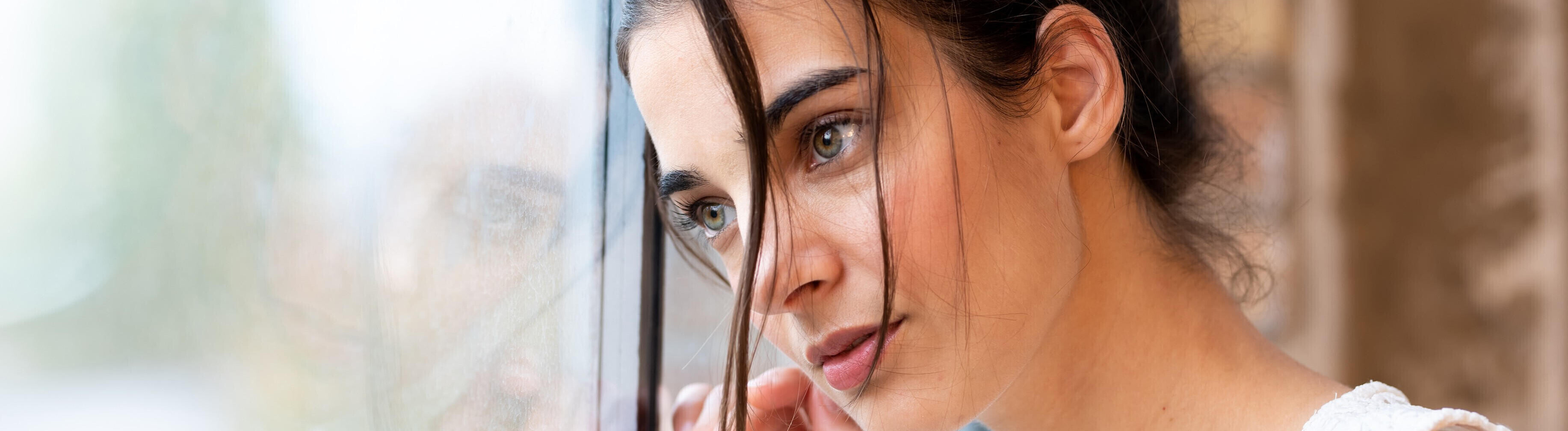 Eine Frau blickt sehnsuchtsvoll aus dem Fenster.