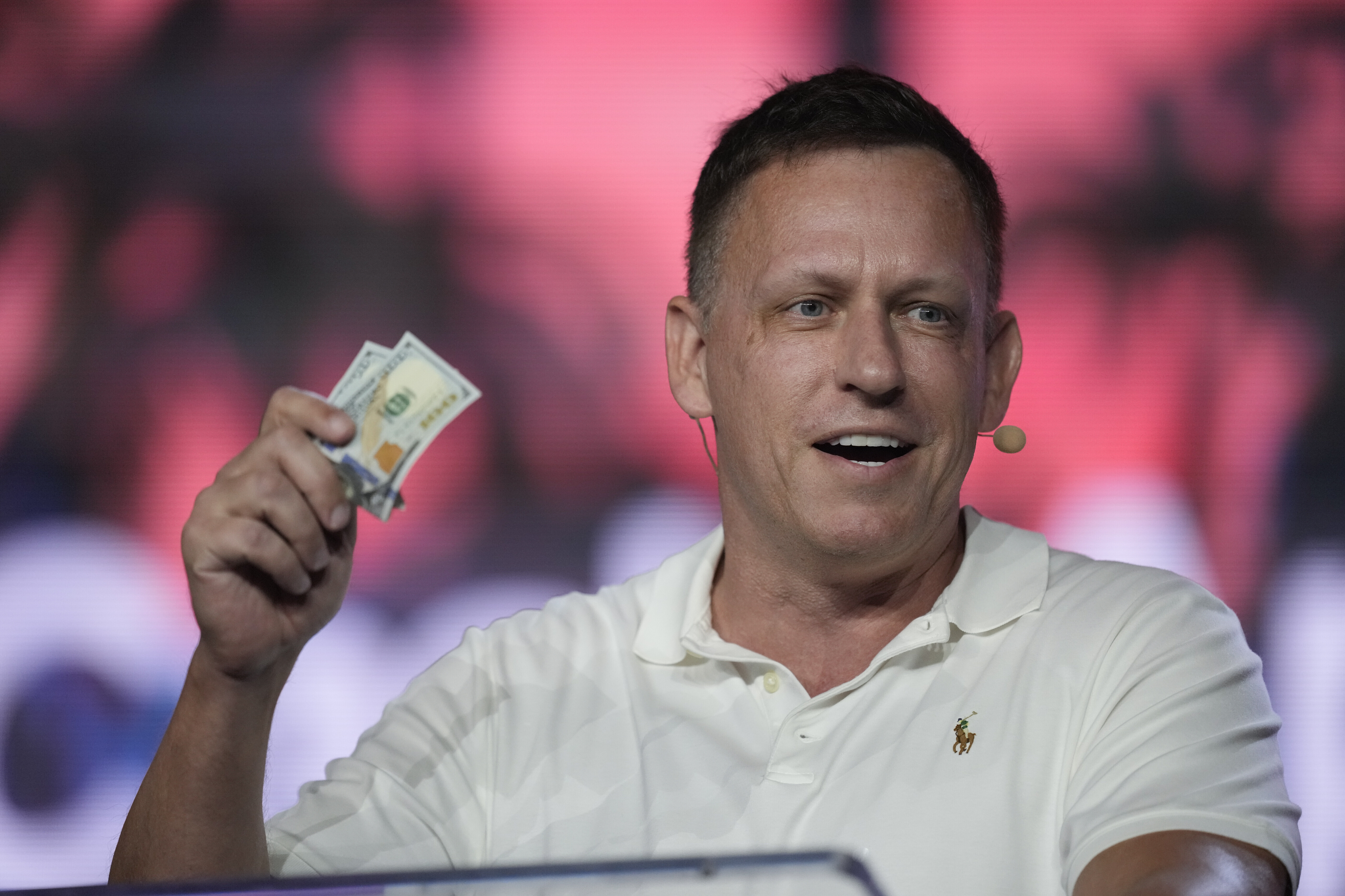 Der US-amerikanische Investor Peter Thiel hält mehrere Dollar-Scheine in der Hand