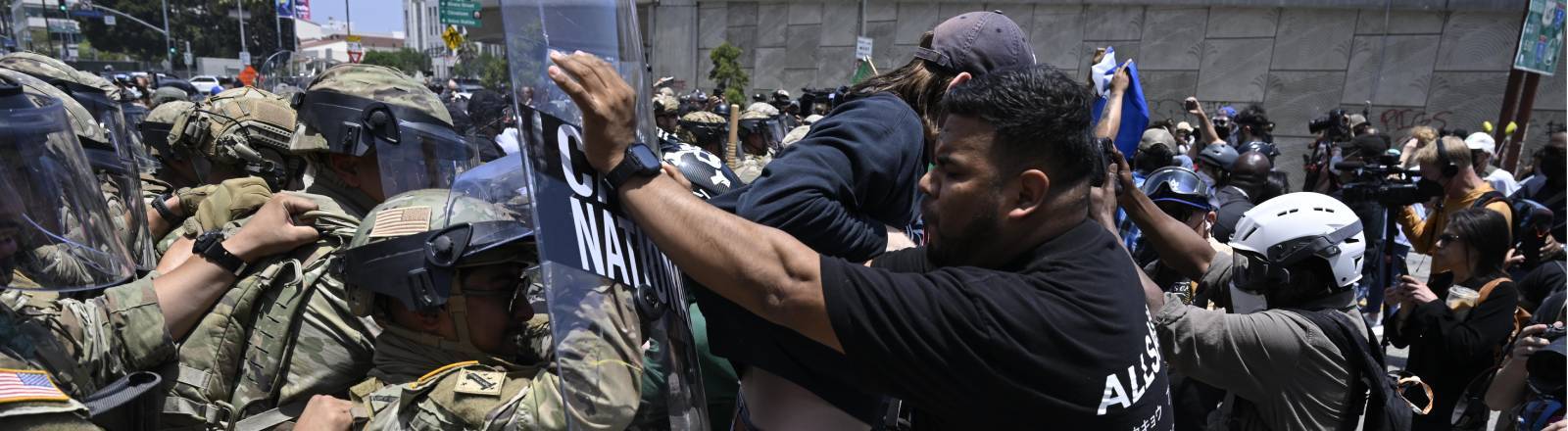 Foto eines Protestierenden in Los Angeles, der inmitten eines Handgemenges zwischen demonstrierenden und Sicherheitskräften im Rahmen der Proteste gegen die Abschiebepolitik Trumps das Schutzschild eines National-Guard-Soldaten wegschiebt