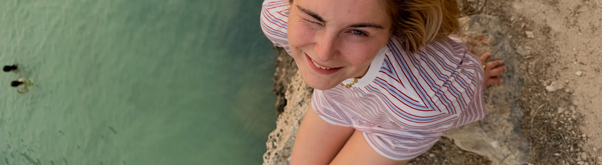 Eine junge Frau namens Nina auf einem Felsen am Meer.