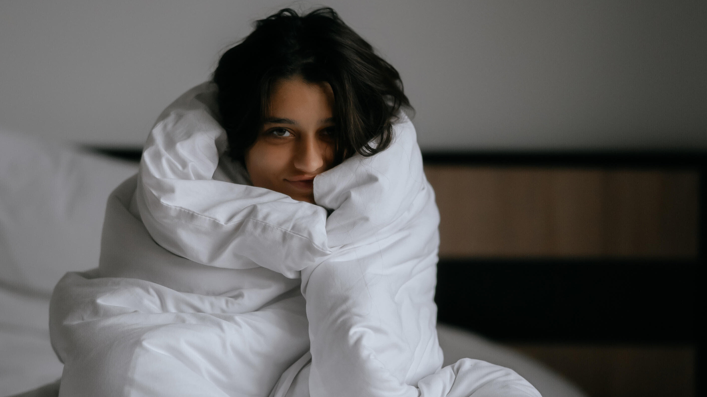 Eine Frau mit Decke um sich im Bett