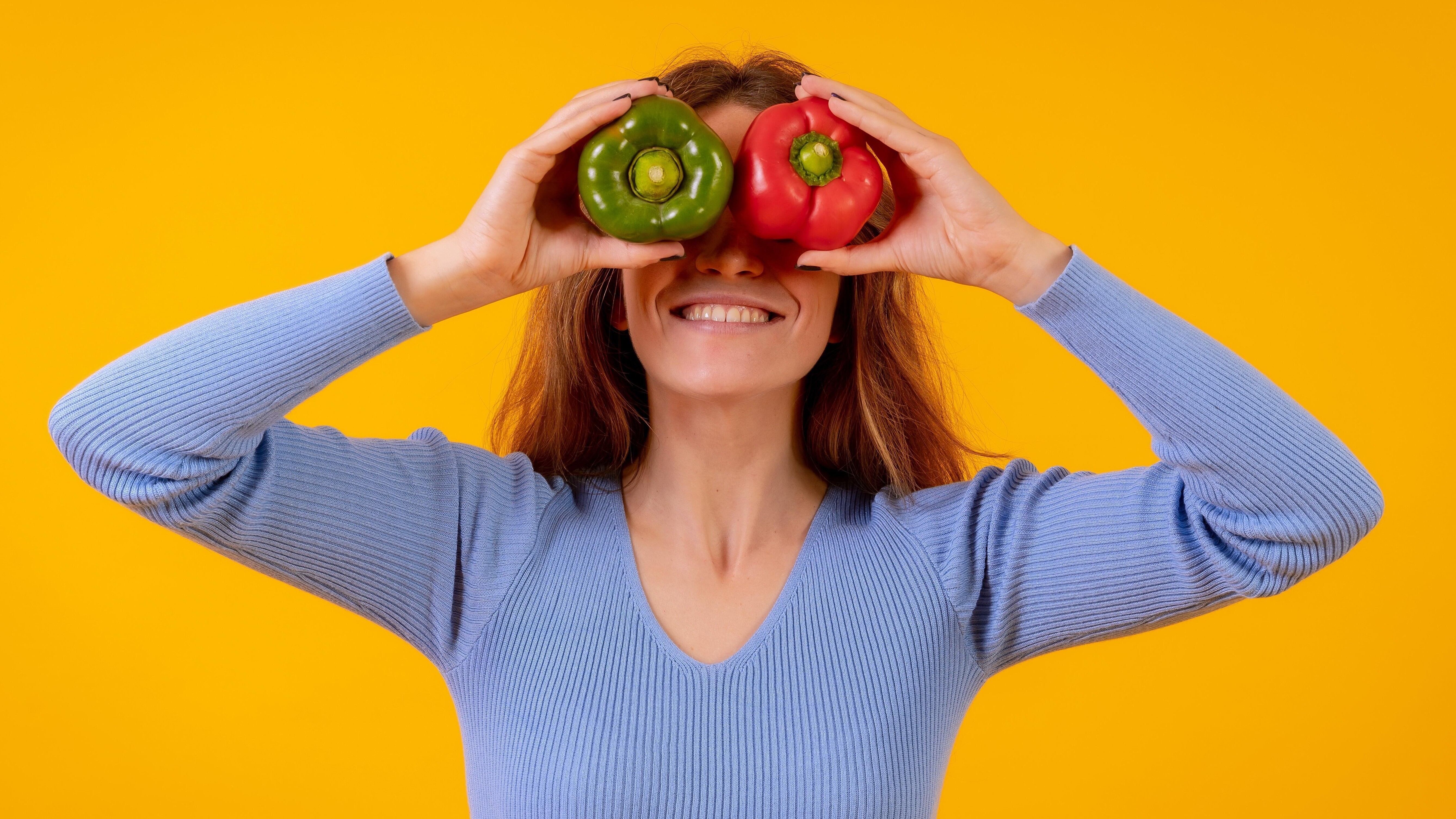 Frau hält sich Paprika vor die Augen