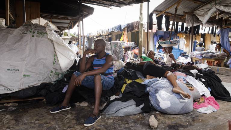 Kantamanto Second-Hand-Textilmarkt in Ghana, Accra. Hier werden Textilien aus der ganzen Welt weiterverarbeitet, verkauft. Verkäufer sitzen an Ständen auf in weißen Säcken verpackte Kleider.