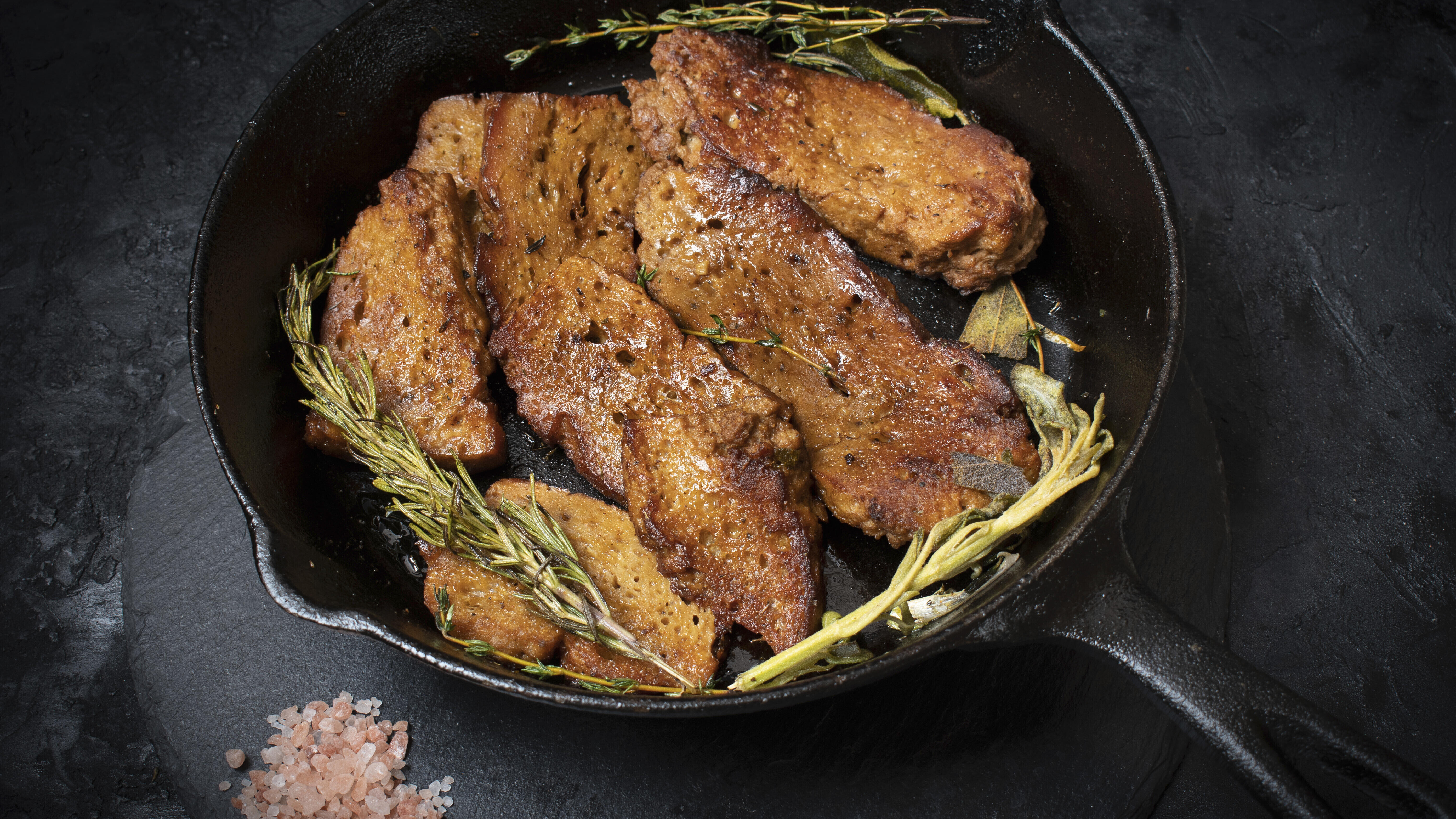 Gebratener Seitan in einer Pfanne mit Kräutern