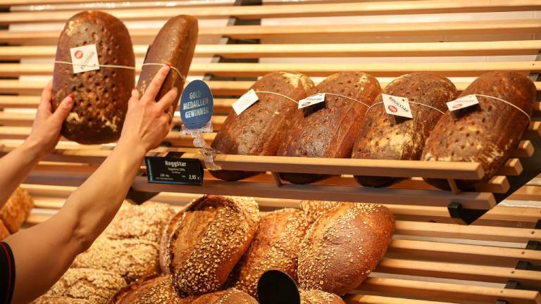 Mitarbeiterin räumt Brot in die Auslage einer Bäckerei