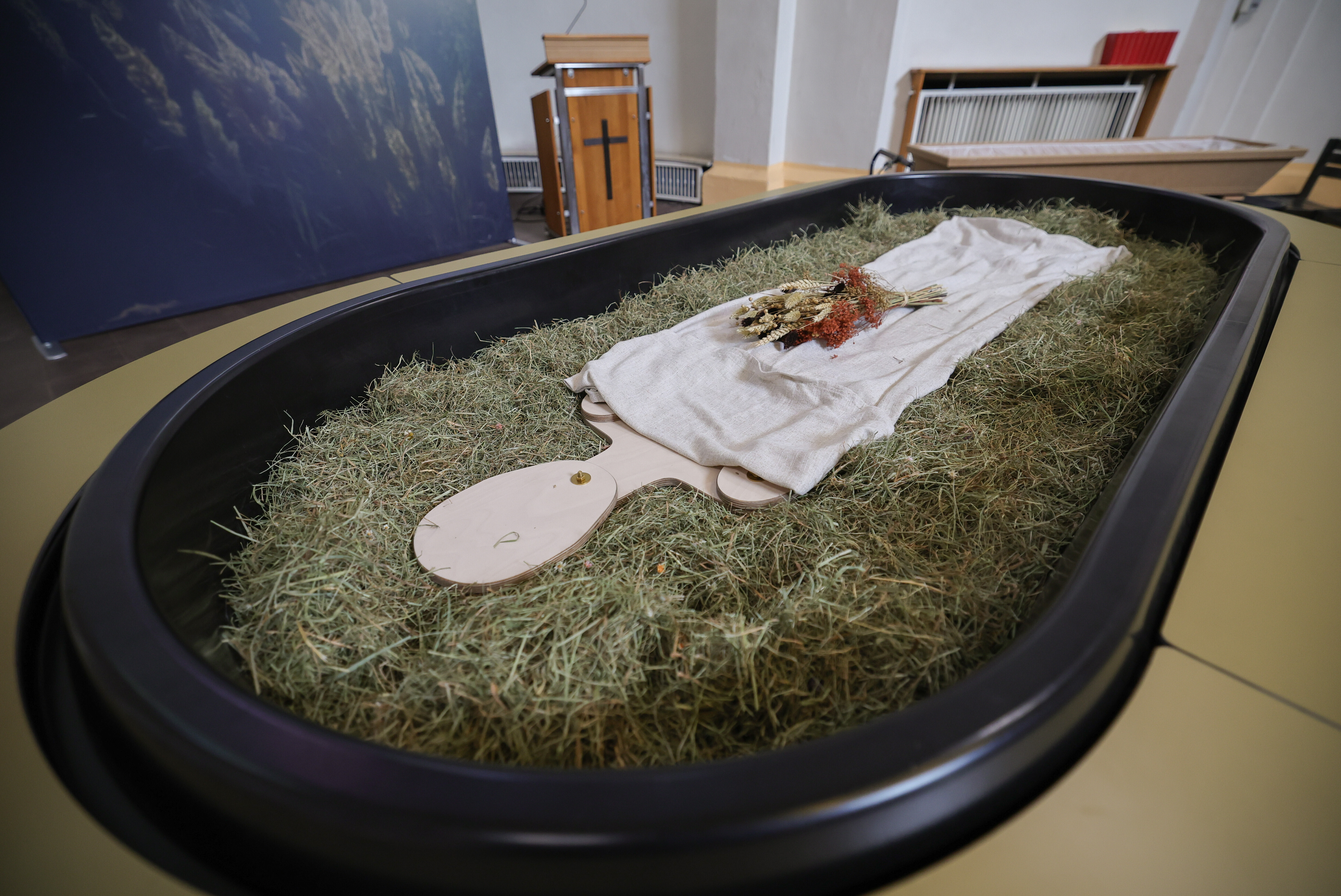 Heu, Stroh, Blumen und eine Holzfigur liegen in einem sogenannten Kokon, der neuen Bestattungsform "Reerdigung"