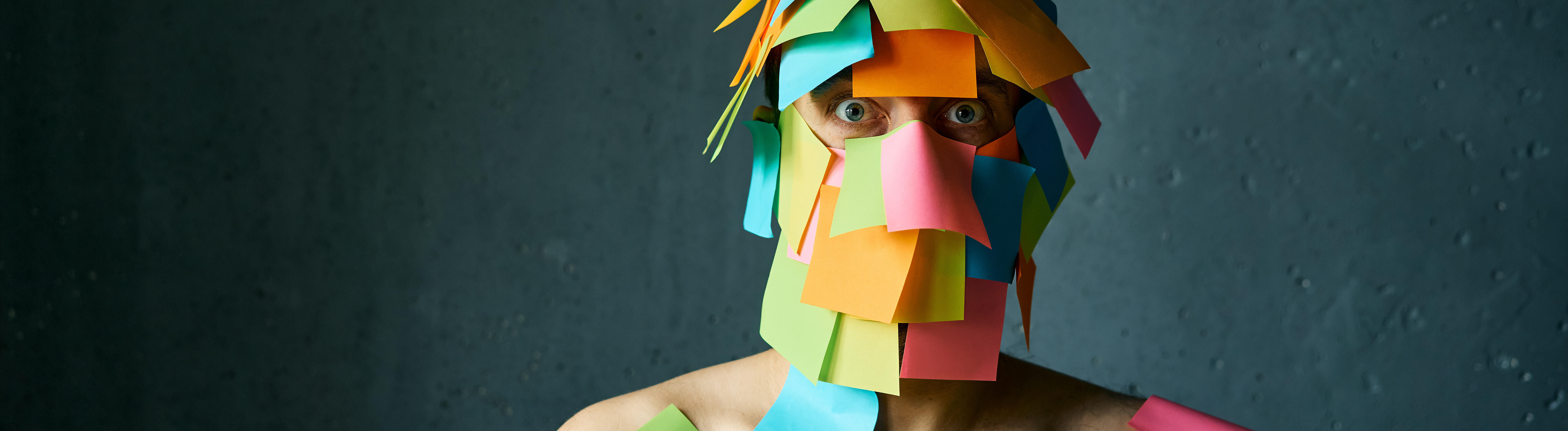 Ein Mann hat viele Post-its-Notes im Gesicht und auf den Schultern kleben und schaut gestresst