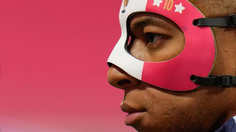 Der französische Nationalspieler Kylian Mbappe im Profil mit pinker Nasen-Maske vor pinkem Hintergrund.