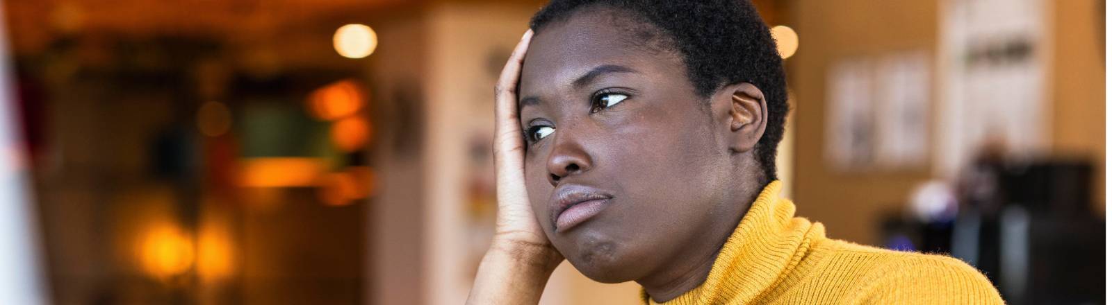 Frau sitzt genervt am Schreibtisch und stützt ihren Kopf auf dem Arm ab