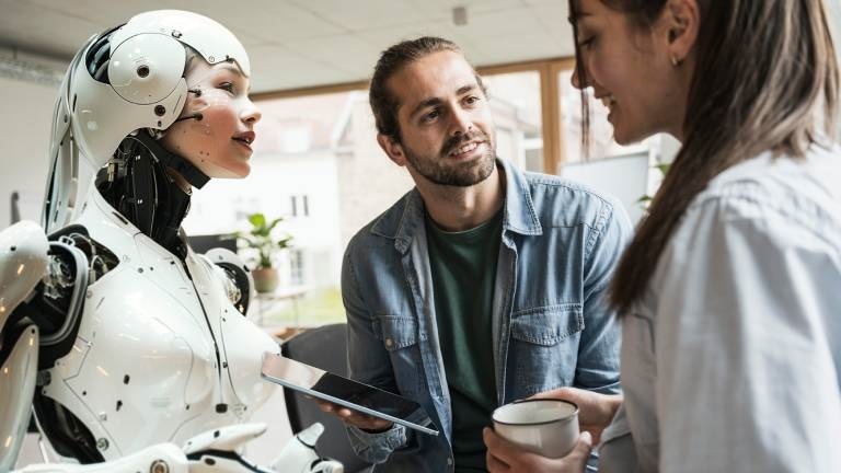 Zwei Mitarbeitende und ein Cyborg stehen zusammen
