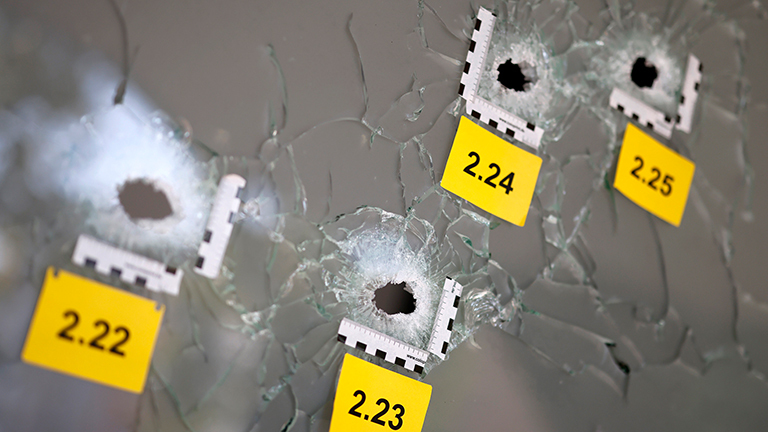 Schusslöcher auf Glasscheibe sind mit polizeilichen Tatortnummern markiert (Köln, 21.09.2024)