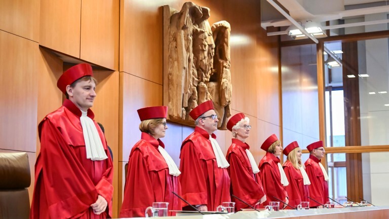 Die Richterinnen und Richter des Bundesverfassungsgerichts stehen zu Beginn einer Verhandlung. Sie tragen rote Roben.