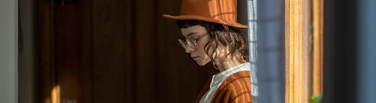 Eine Frau steht am Fenster und blickt traurig unten