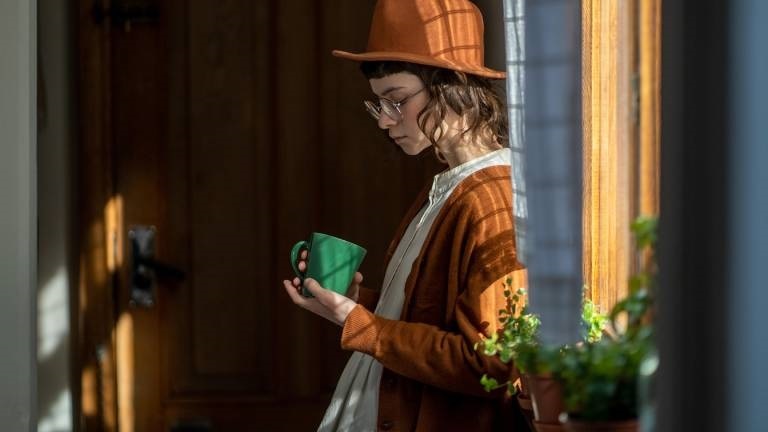 Eine Frau steht am Fenster und blickt traurig unten