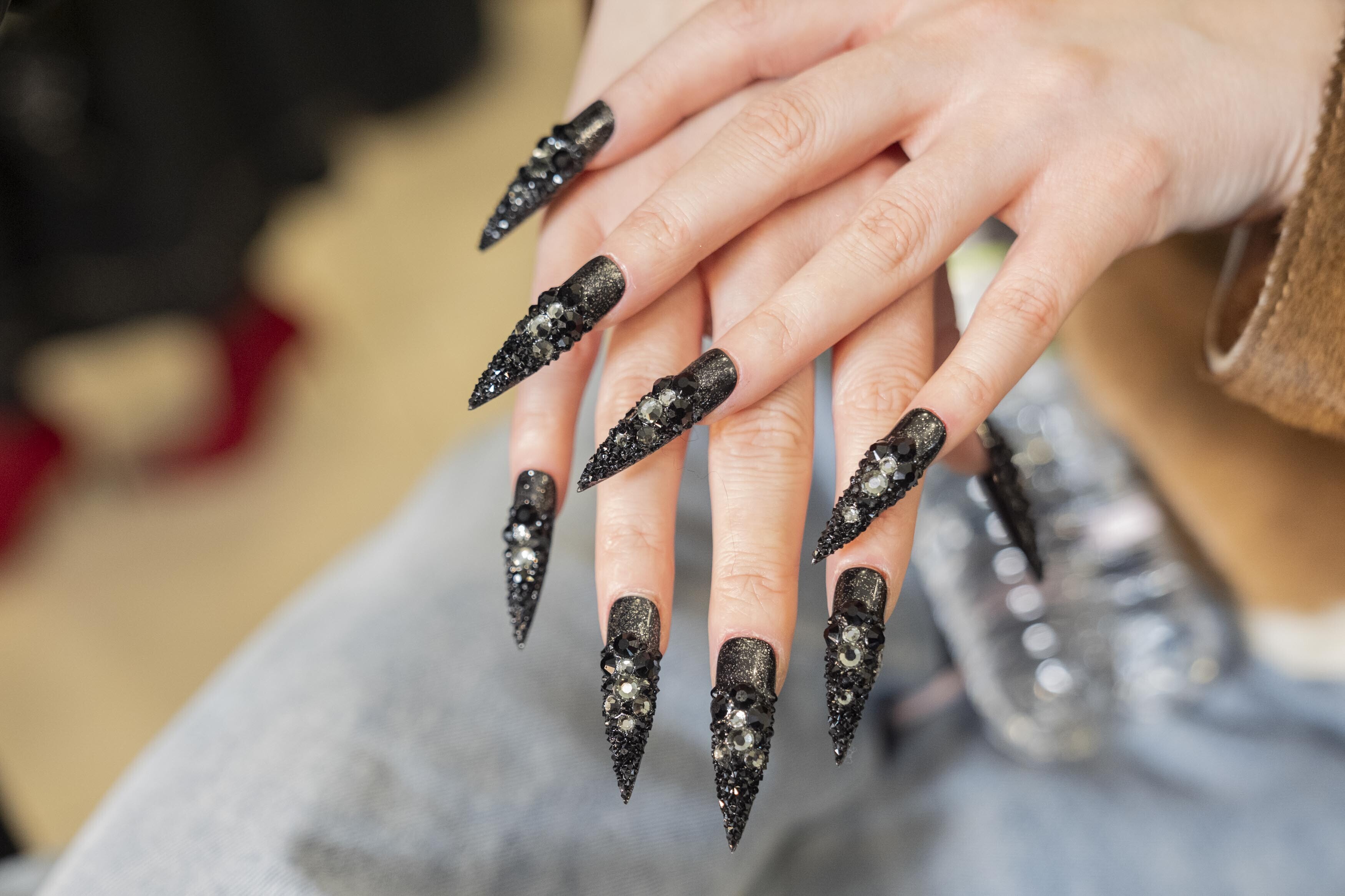 Nahaufnahme von langen schwarz lackierten Fingernägeln