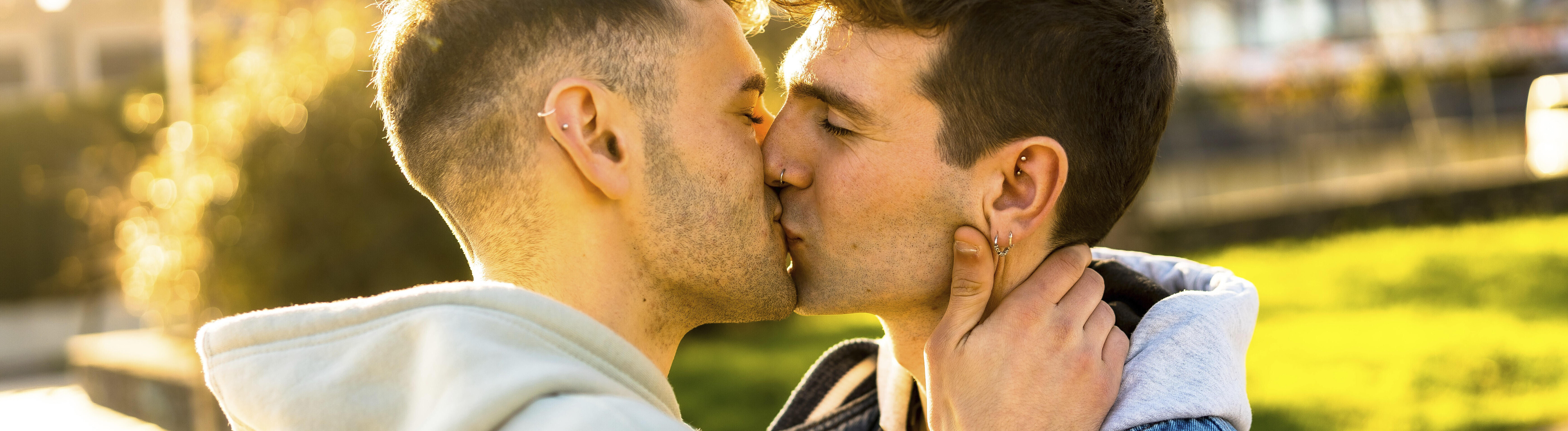 Zwei männlich gelesene Personen küssen sich auf den Mund.