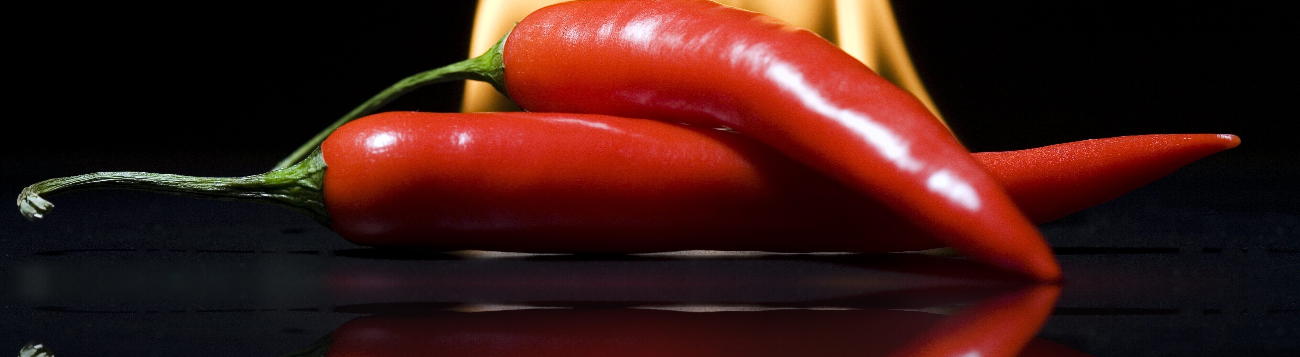 Zwei Peperonios vor Flammen im Hintergrund