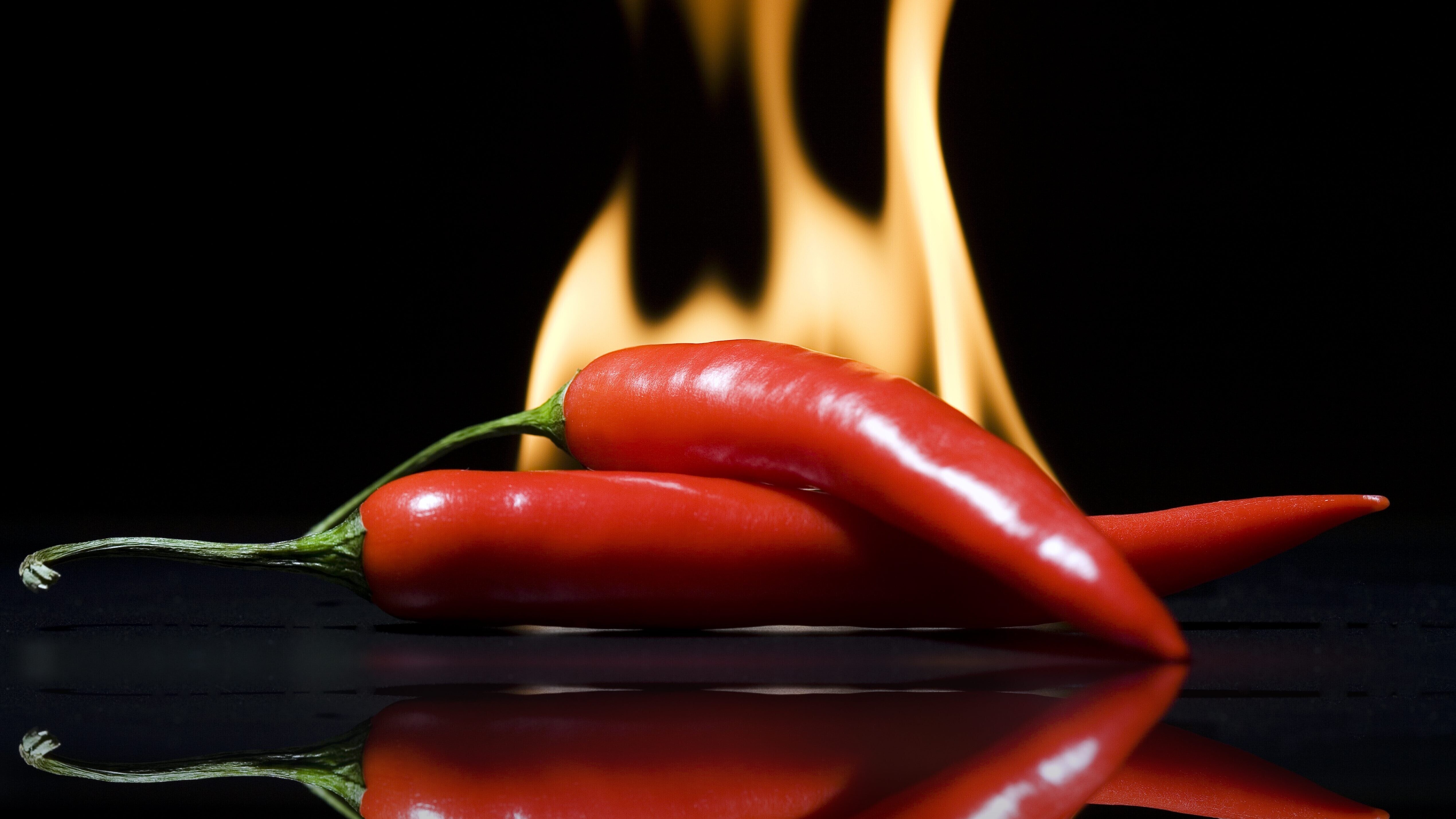 Zwei Peperonis mit Flammen im Hintergrund