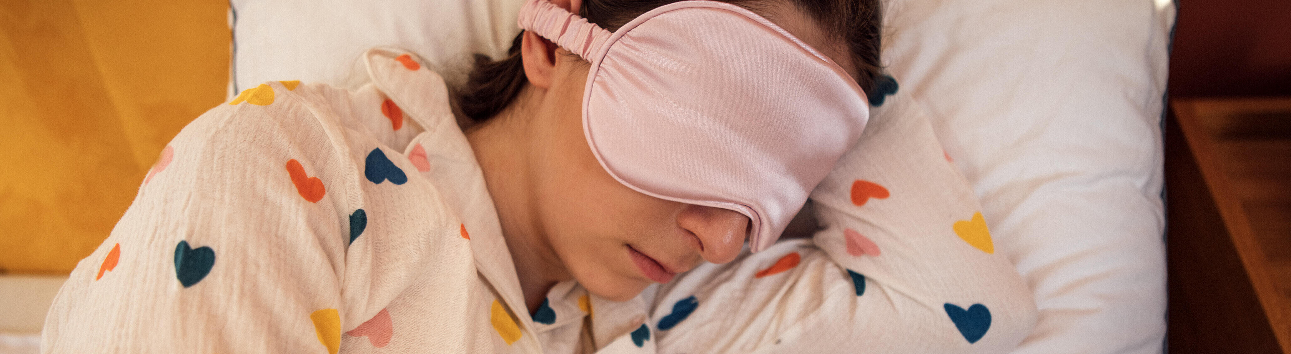 Eine Frau liegt mit einer Schlafmaske im Bett