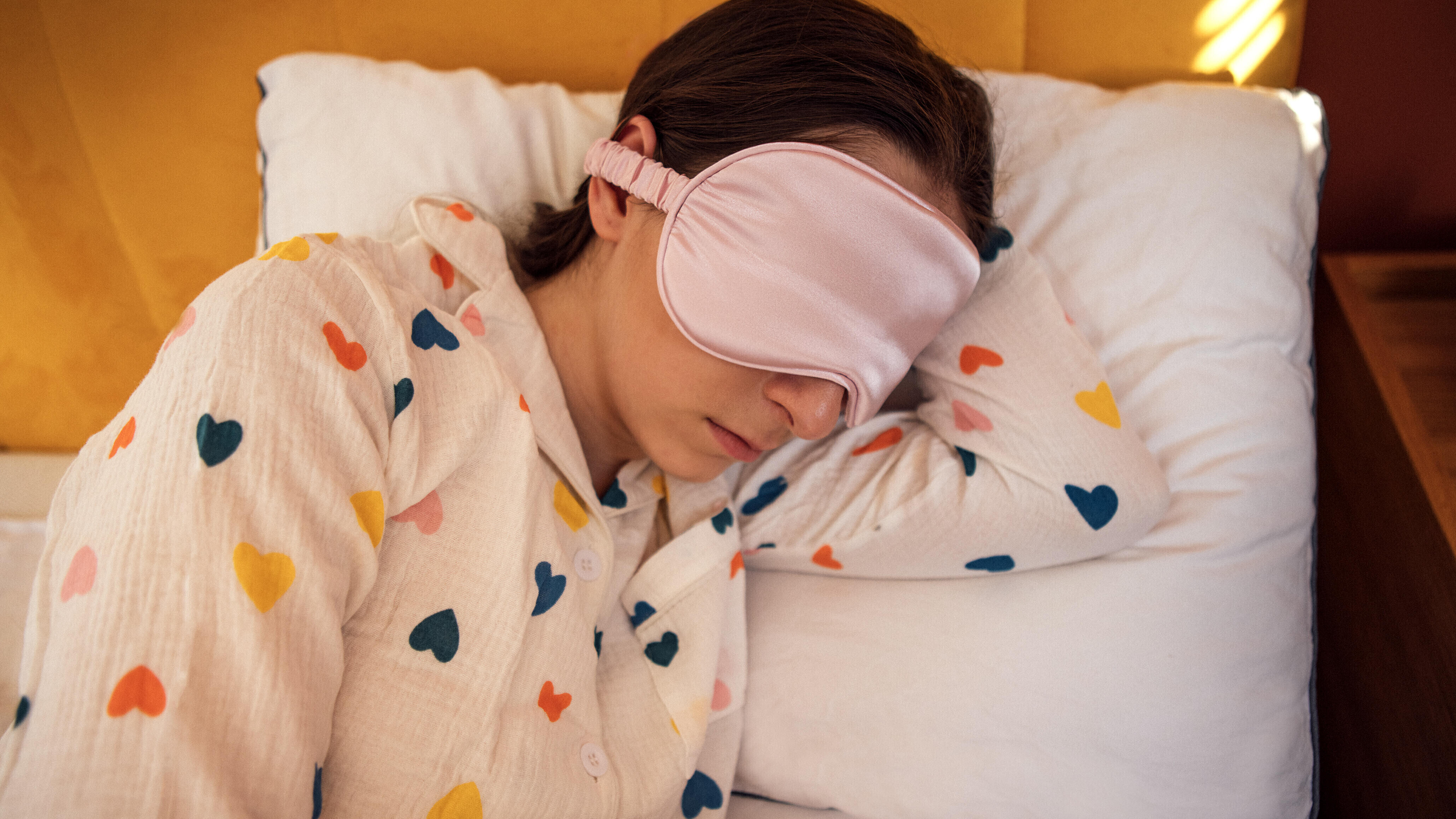 Eine Frau liegt mit einer Schlafmaske im Bett