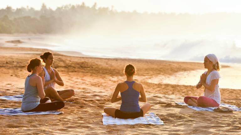 Eine Gruppe macht zusammen Yoga am Strand