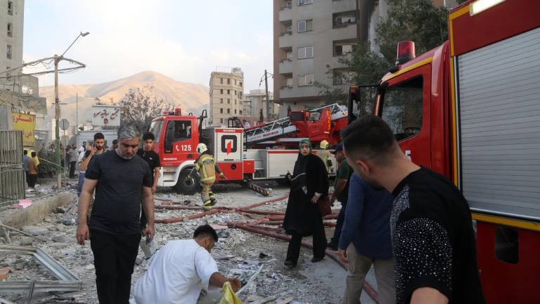 Feuerwehrwagen und Menschen vor zerstörtem Gebäude in Teheran (Iran), das bei einem israelischen Luftangriff getroffen wurde (13.6.2025)