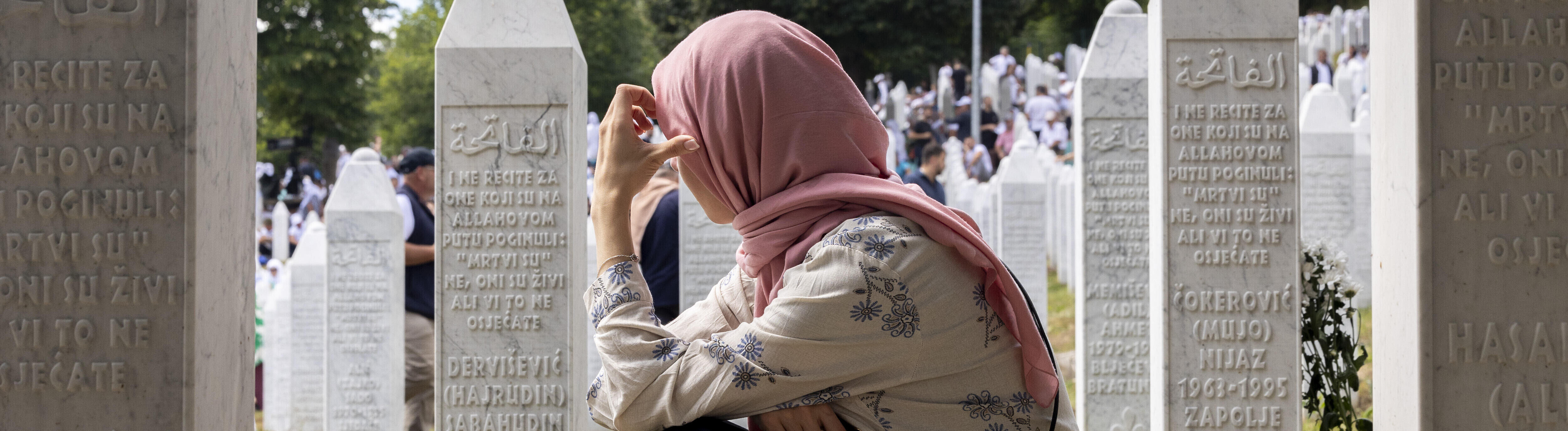 Eine Frau kniet am Mahnmal von Srebrenica.