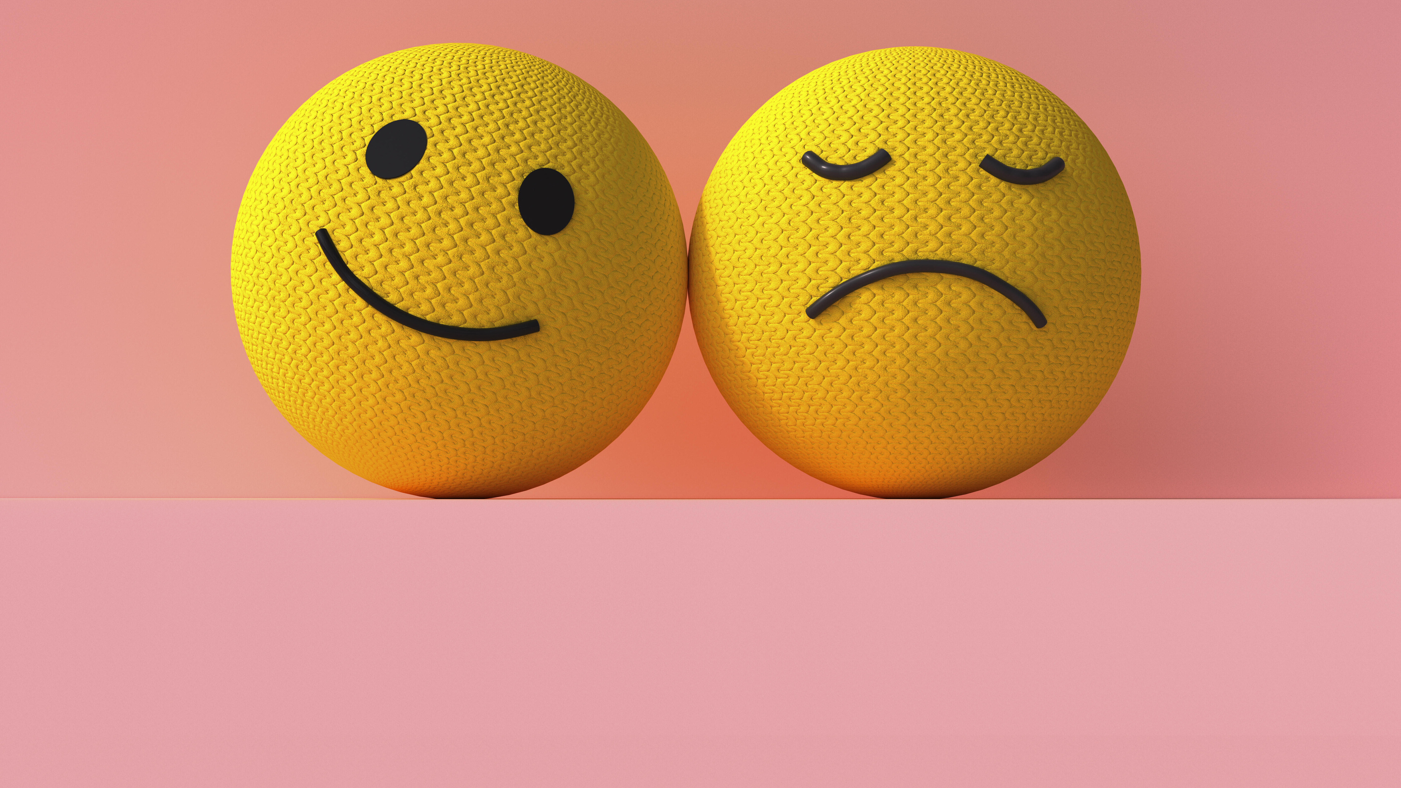 Zwei 3D-Smiley-Emojis sind nebeneinander. Das rechte Emoji lächelt, das linke Emoji ist traurig.