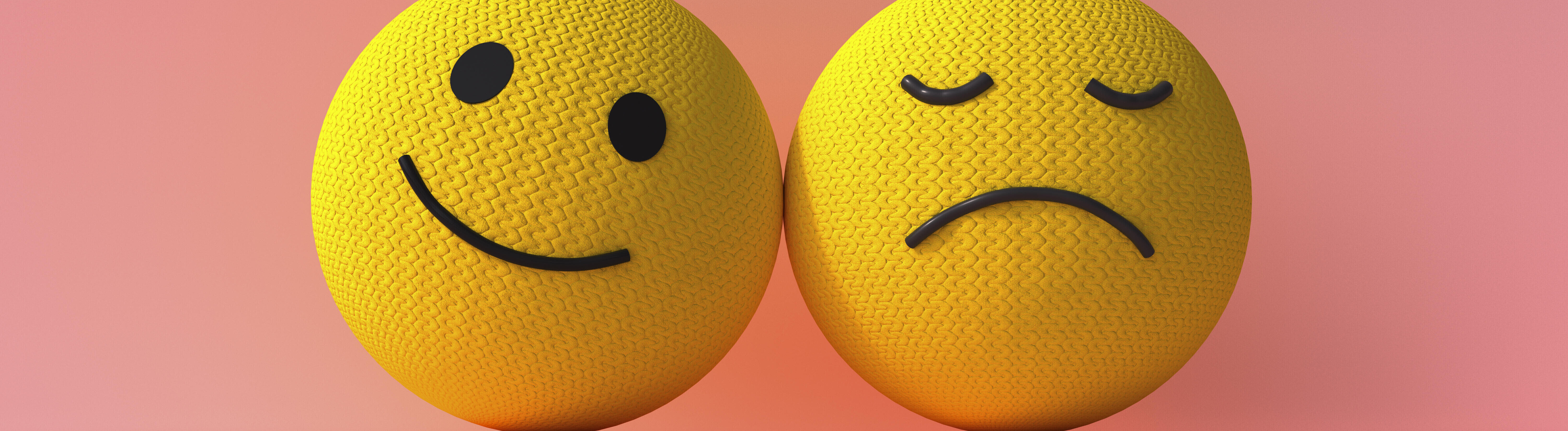 Zwei 3D-Smiley-Emojis sind nebeneinander. Das rechte Emoji lächelt, das linke Emoji ist traurig.