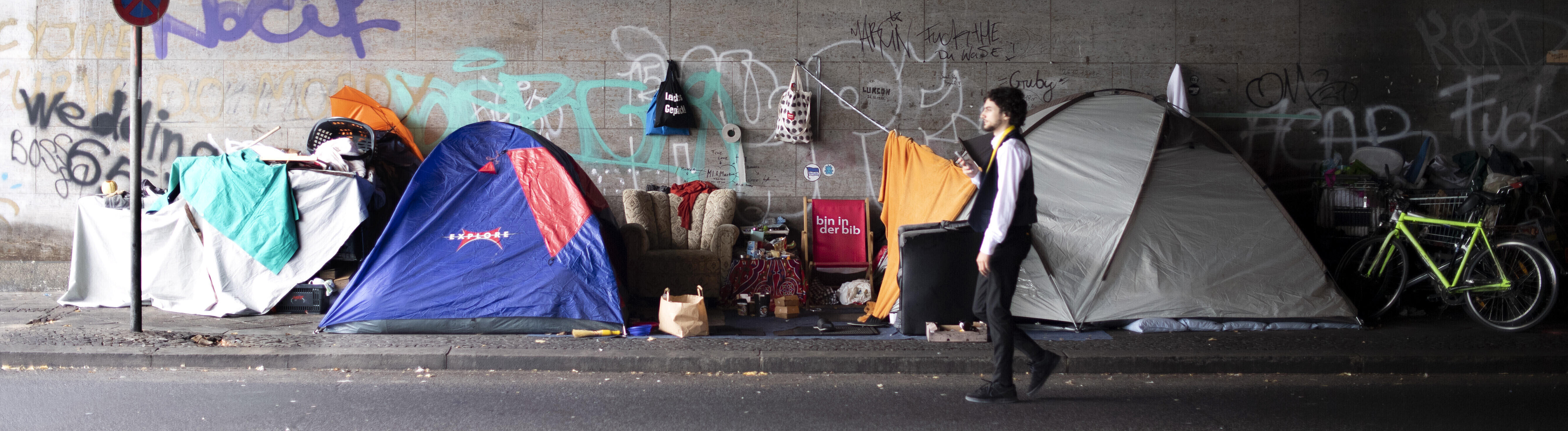 Ein Mann geht in einer Unterführung  an mehreren Zelten vorbei (25.08.2022)