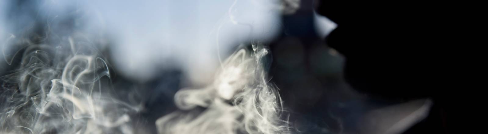 Person atmet Rauch aus