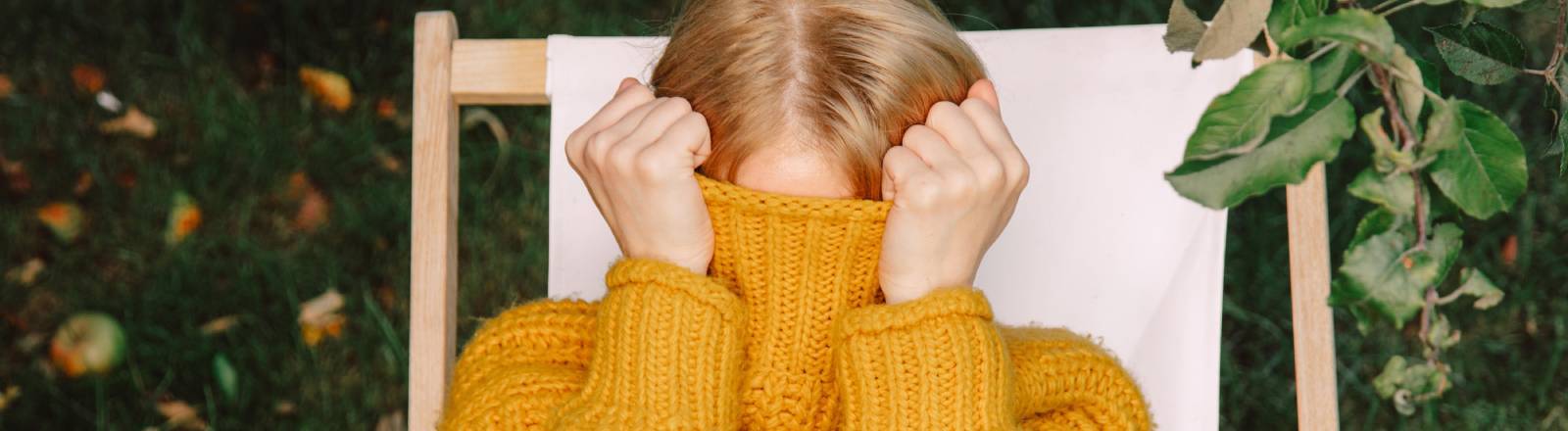 Eine Frau versteckt ihr Gesicht hinter ihrem Pullover