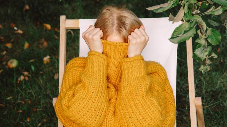 Eine Frau versteckt ihr Gesicht hinter ihrem Pullover