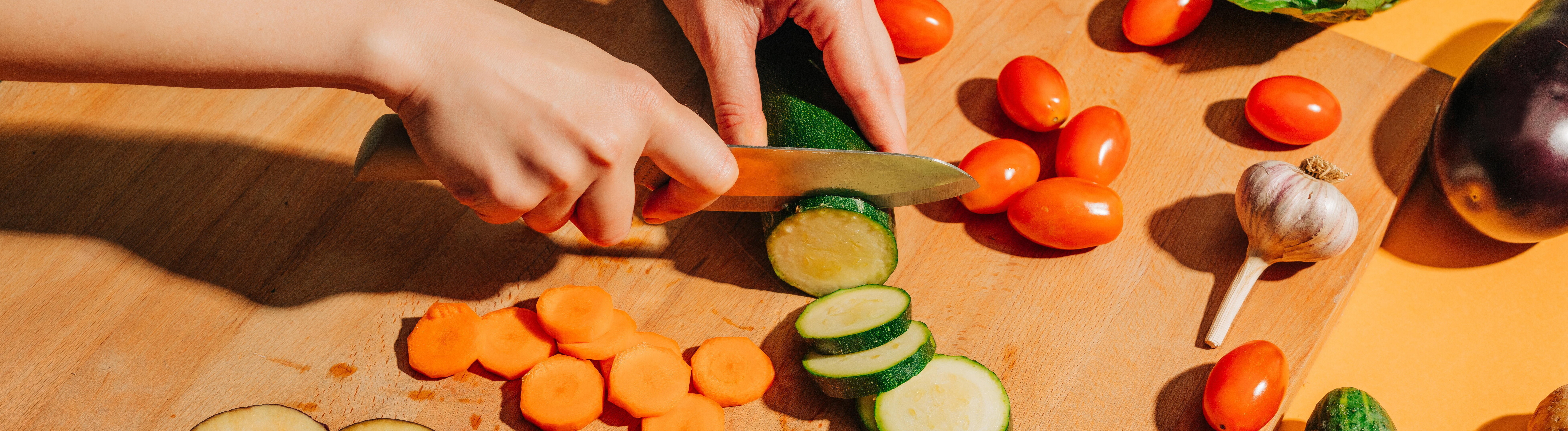 Eine Frau schneidet Gemüse klein auf einem großen Brett.